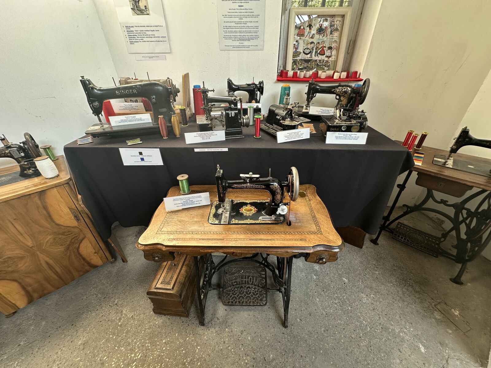 Machines à coudre anciennes présentées sur des tables drapées de noir